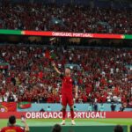Il calciatore Cristiano Ronaldo saluta il pubblico sugli spalti di uno stadio gremito di tifosi.